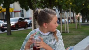 Parktaki şehir merkezinde genç bir kız bir yaz akşamı limonata içer.