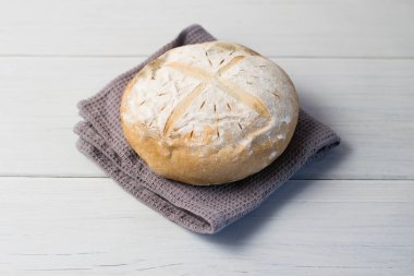 Gri bir havlunun üzerindeki ışık masasında taze pişmiş lezzetli beyaz ekmek. Lezzetli ev yapımı yemekler..