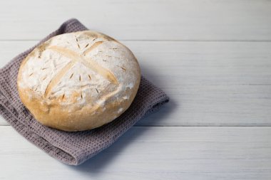 Gri bir havlunun üzerindeki ışık masasında taze pişmiş lezzetli beyaz ekmek. Lezzetli ev yapımı yemekler..