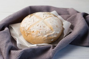Gri bir havlunun üzerindeki ışık masasında taze pişmiş lezzetli beyaz ekmek. Lezzetli ev yapımı yemekler..