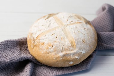 Gri bir havlunun üzerindeki ışık masasında taze pişmiş lezzetli beyaz ekmek. Lezzetli ev yapımı yemekler..