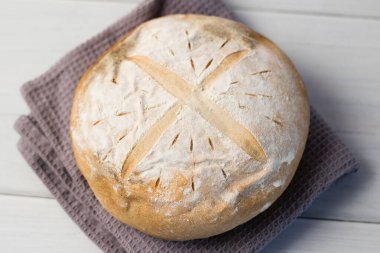 Gri bir havlunun üzerindeki ışık masasında taze pişmiş lezzetli beyaz ekmek. Lezzetli ev yapımı yemekler..