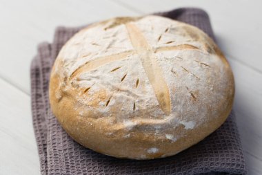 Gri bir havlunun üzerindeki ışık masasında taze pişmiş lezzetli beyaz ekmek. Lezzetli ev yapımı yemekler..