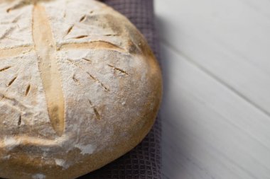 Gri bir havlunun üzerindeki ışık masasında taze pişmiş lezzetli beyaz ekmek. Lezzetli ev yapımı yemekler..