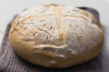 Gri bir havlunun üzerindeki ışık masasında taze pişmiş lezzetli beyaz ekmek. Lezzetli ev yapımı yemekler..