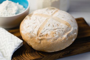 Gri bir havlunun üzerindeki ışık masasında taze pişmiş lezzetli beyaz ekmek. Lezzetli ev yapımı yemekler.