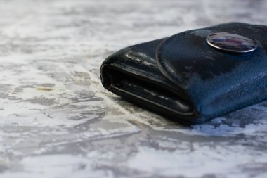 Aydınlık bir masada eski gri bir cüzdan.