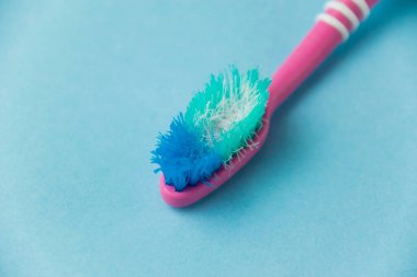 Düzgün diş fırçalama ve oral bakım kavramı. Eski kullanılmış diş fırçası mavi arka planda yakın plan