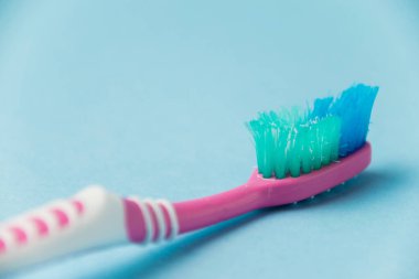 Düzgün diş fırçalama ve oral bakım kavramı. Eski kullanılmış diş fırçası mavi arka planda yakın plan
