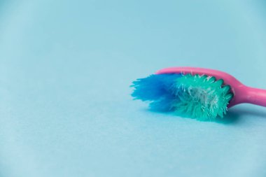 Düzgün diş fırçalama ve oral bakım kavramı. Eski kullanılmış diş fırçası mavi arka planda yakın plan
