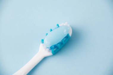 Açık arkaplanda diş macunlu mavi diş fırçası..