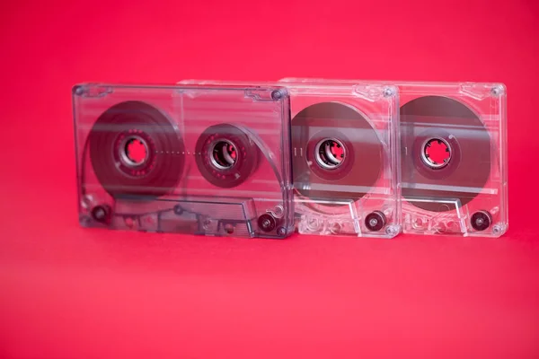 Three plastic audio tape cassettes on red background