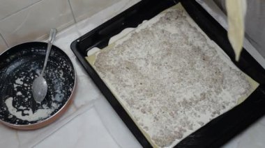 Kadın hamur ile etli turta pişiriyor.