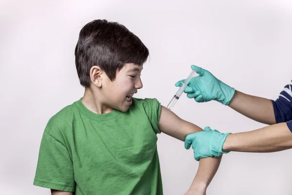 Junge blickt auf Nadel im Arm. — Stockfoto