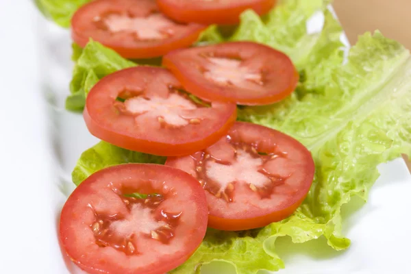 Skivade tomater på bladen av sallad. — Stockfoto