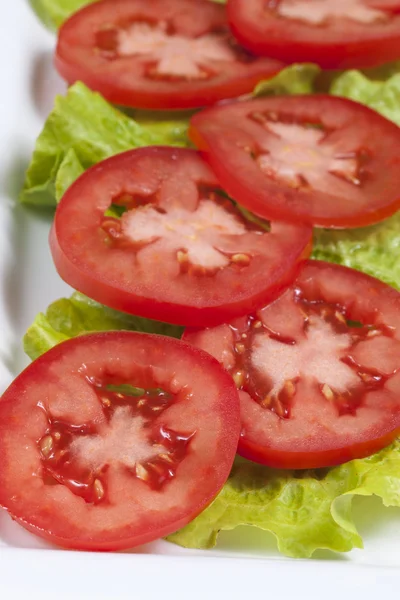 Teller mit Tomaten auf Salat. — Stockfoto