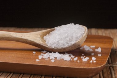 Kesme tahtası üzerinde deniz tuzu kaşıkla.