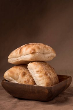 Tahta bir kaseye yerleştirilmiş üç ciabatta rulosunun stüdyo fotoğrafı..