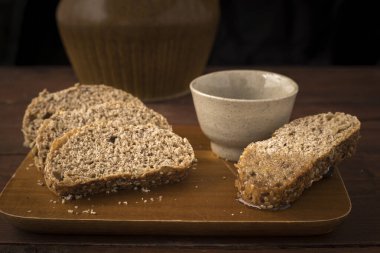 Buğday ekmeği küçük bir bardak zeytinyağıyla kesme tahtasına dilimler..