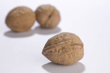 Ön planda bir ceviz sergilenir ve iki tanesi beyaz arka plandadır..