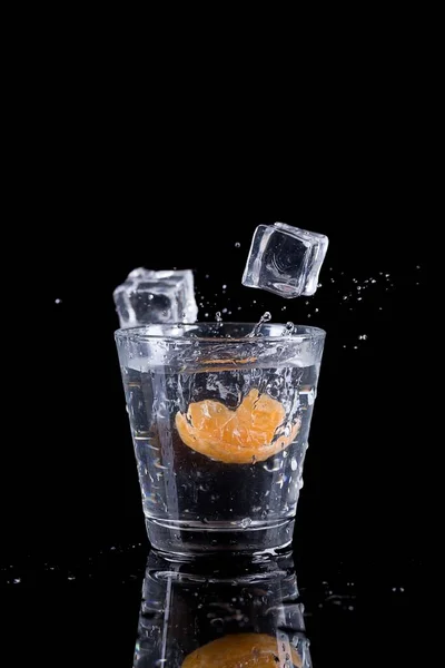 오렌지 조각이 유리잔에 얼음을 스튜디오 사진을 떨어뜨린다 — 스톡 사진