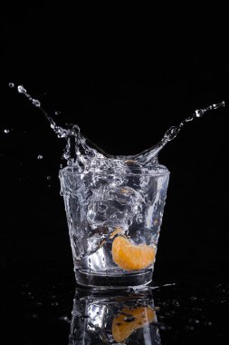 Stüdyoda çekilen portakal dilimli buz küplerinin suya atıldığı bir fotoğraf..