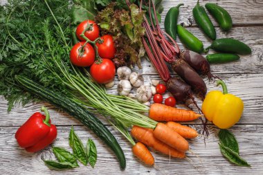 Tahta bir masada çeşitli sebzeler ve fesleğenler..
