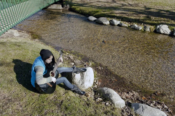 Jouer de sa guitare par un ruisseau . — Photo