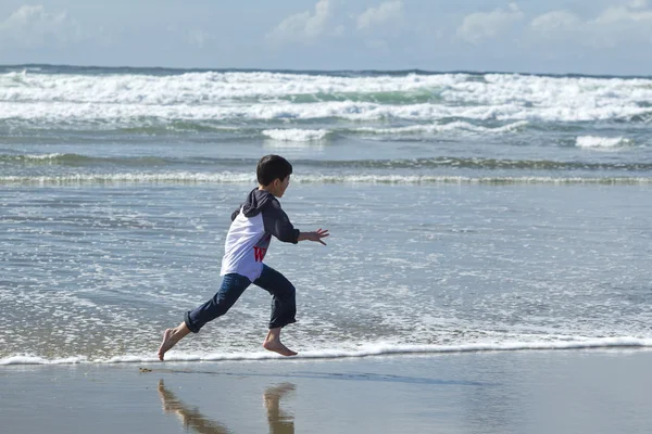 Jongen loopt op strand. — Stockfoto