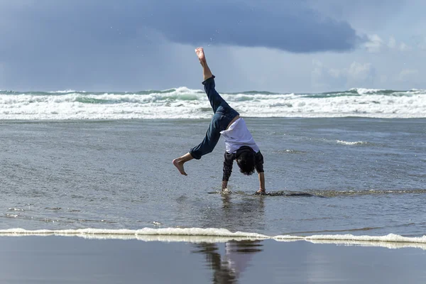 Jongen cartwheel op het strand. — Stockfoto