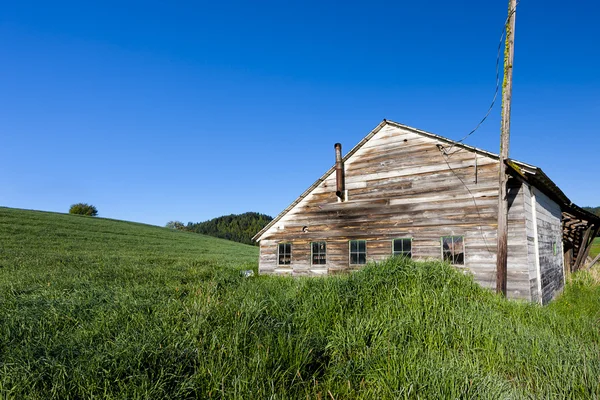 Old shed by grassy hill. — Stock Photo, Image