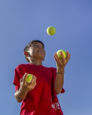 Boy juggles tennis balls. clipart