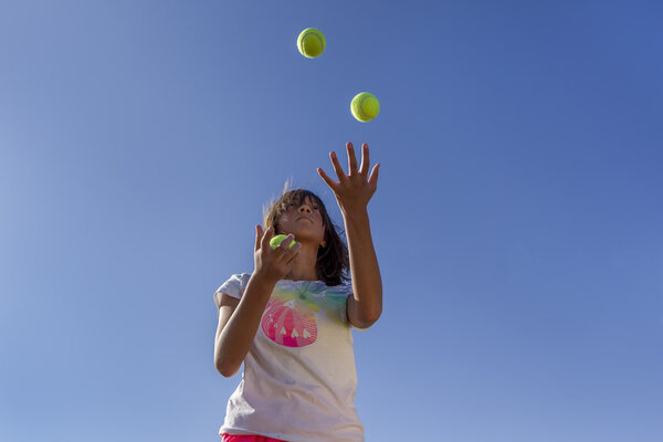 Juggling tennis balls.
