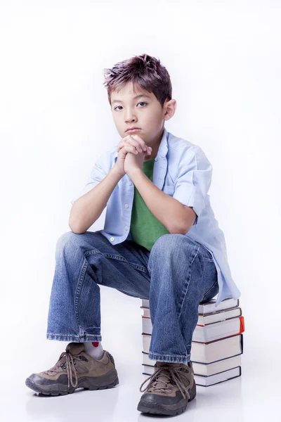Pojken sitter på böcker. — Stockfoto