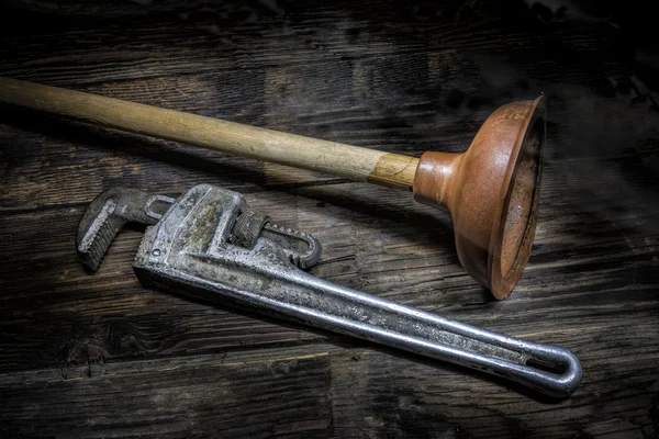 Old plunger and pipe wrench. — Stock Photo, Image