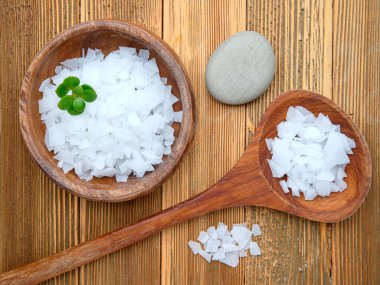 Tahta bir kasede magnezyum klorür taneciklerinin düz bir fotoğrafı ve tahta bir masada kaşık..
