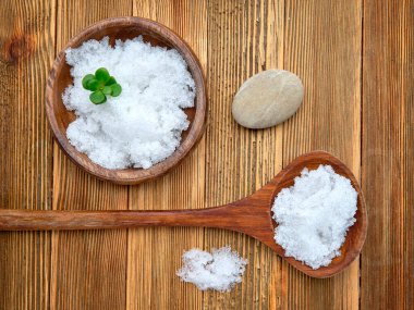 Tahta bir kasede ölü deniz tuzu ve tahta bir masada kaşığın düz bir fotoğrafı..