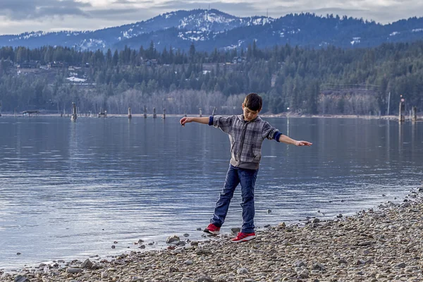 Boy spins around by lakefront. — Stock Photo, Image