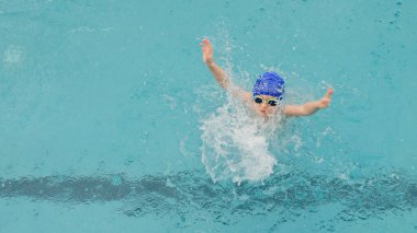 Yüzme havuzunda oynayan ve yüzen 7 yaşındaki bir çocuğun en iyi görüntüsü.