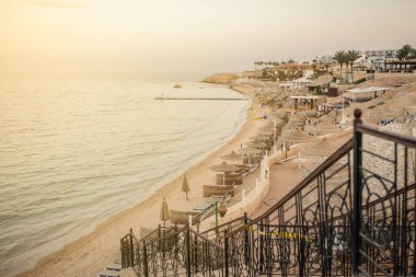 Yaz tatili için cennet gibi bir tropik tatil beldesindeki kumsalda Thatched plaj şemsiyeleri ve şezlongları