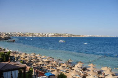 Yaz tatili için cennet gibi bir tropik tatil beldesindeki kumsalda Thatched plaj şemsiyeleri ve şezlongları