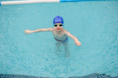 Yüzme havuzunda oynayan ve yüzen 7 yaşındaki bir çocuğun en iyi görüntüsü.