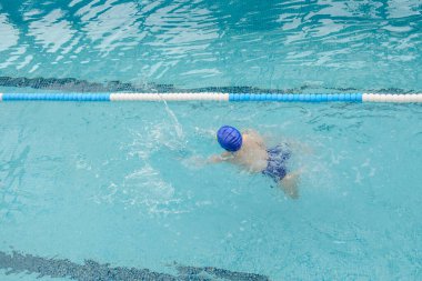 Yüzme havuzunda oynayan ve yüzen 7 yaşındaki bir çocuğun en iyi görüntüsü.