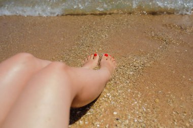 Sahilde kadının bacaklarının yan görüntüsü.