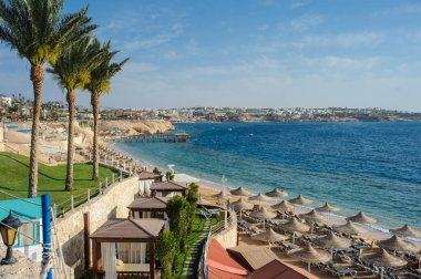 Yaz tatili için cennet gibi bir tropik tatil beldesindeki kumsalda Thatched plaj şemsiyeleri ve şezlongları