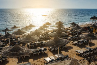 Yaz tatili için cennet gibi bir tropik tatil beldesindeki kumsalda Thatched plaj şemsiyeleri ve şezlongları