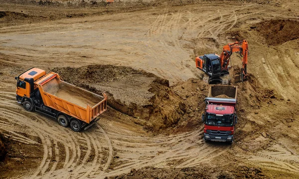 Industrial truck loader excavator moving earth and unloading into a dumper truck and bulldozer is moving ground