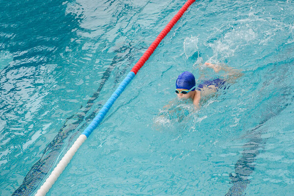 top view of a 7-year boy playing and swimming in the swimming pool