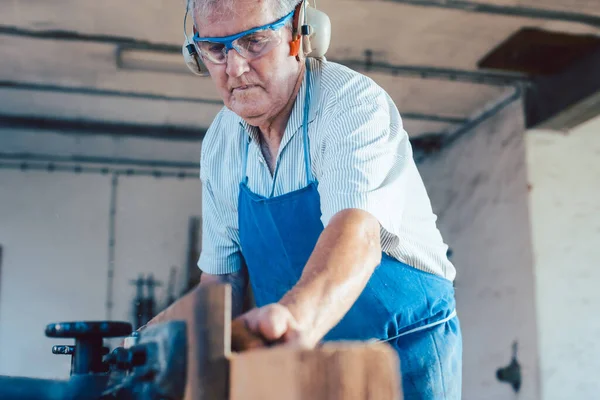 Menuisier senior travaillant avec raboteuse à bois sur pièce — Photo