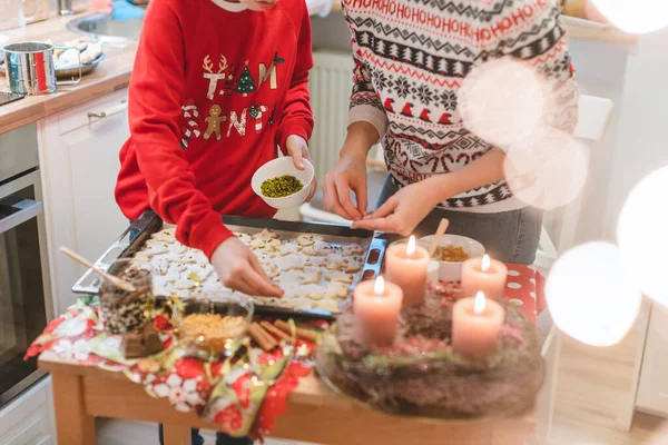 Мать и сын украшают рождественское печенье на простыне — стоковое фото